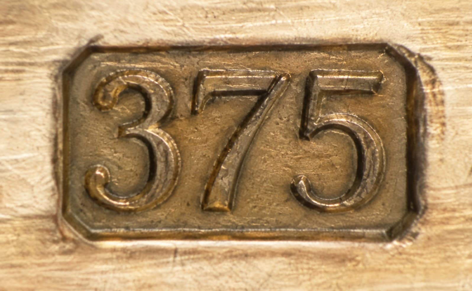 Close-up of a 375 gold stamp on a vintage textured piece of jewelry