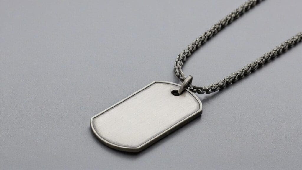 Single blank stainless steel dog tag pendant on silver chain necklace against gray background, showing polished metal finish and rounded corners