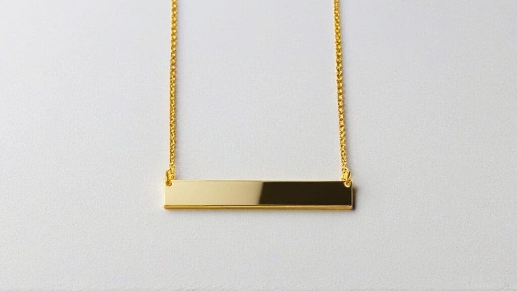 Gold bar necklace perfect for engraving names - classic personalized jewelry piece with polished finish on neutral background