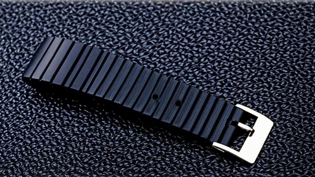 Black rubber watch band with buckle and adjustment holes showing ridged texture and metal clasp