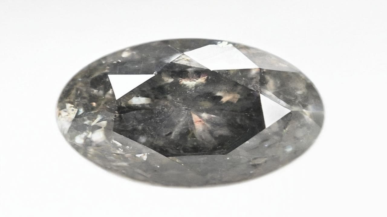 Oval salt-and-pepper diamond speckled with black and white inclusions
