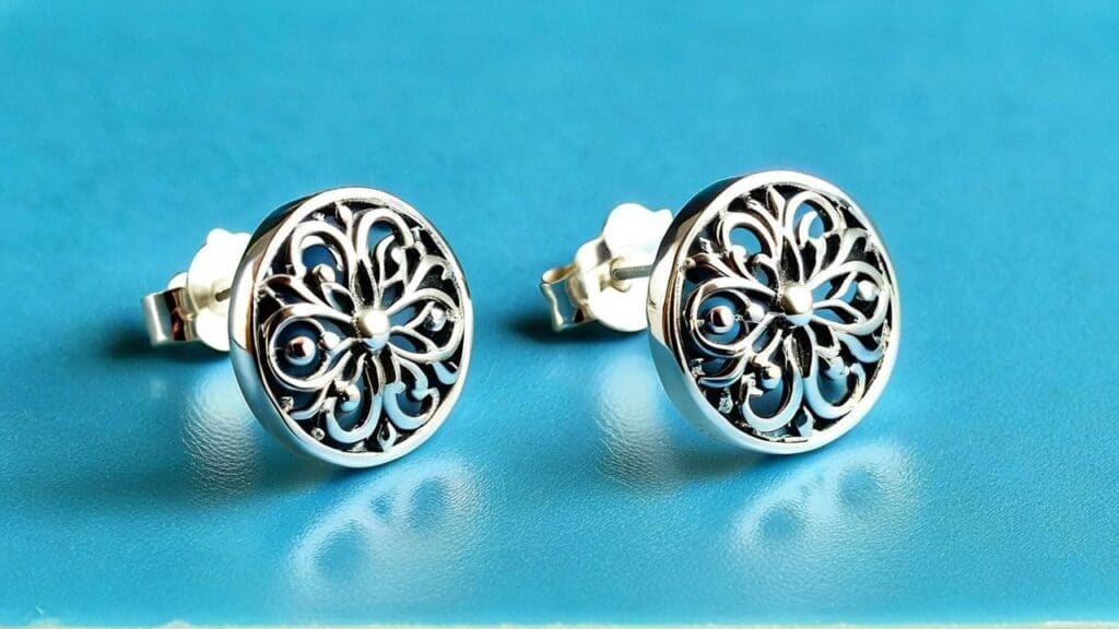 Pair of sterling silver filigree stud earrings with intricate floral pattern and high polish finish