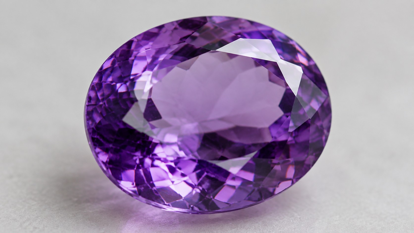 Faceted purple amethyst gemstone on a neutral background