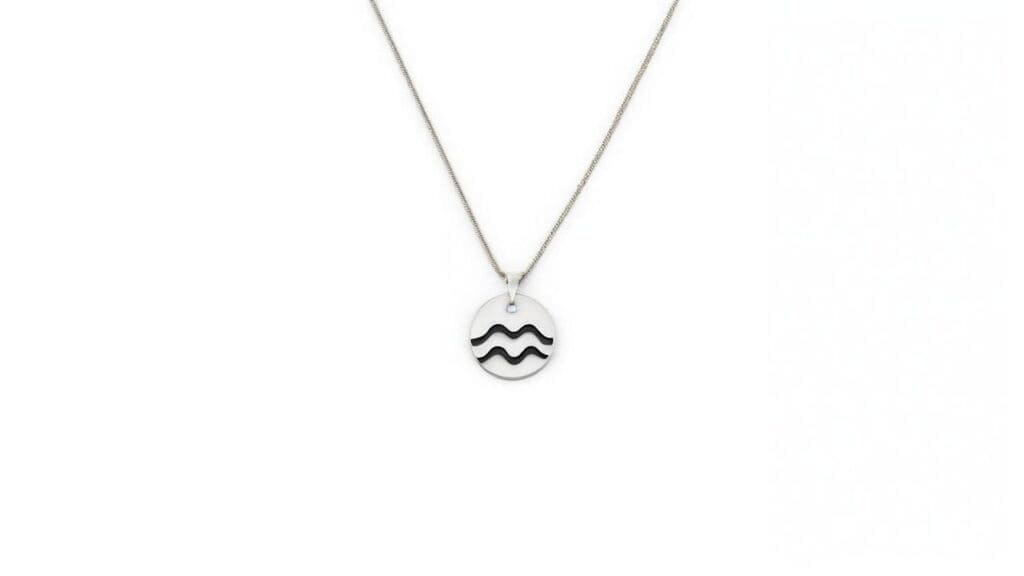 Minimalist silver Aquarius zodiac pendant featuring black wavy symbol on simple oval disc with delicate chain