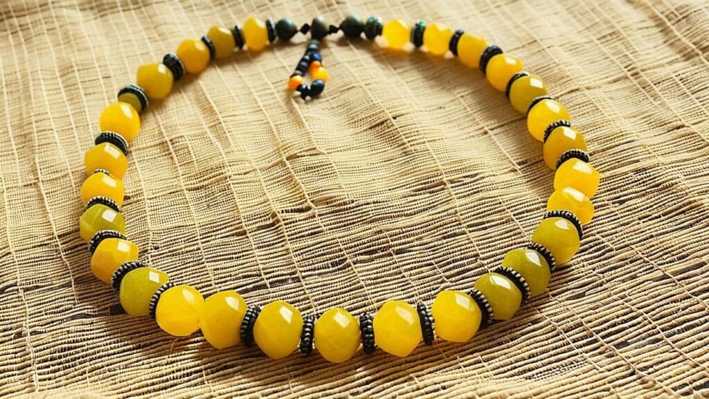 Beaded necklace made of faceted yellow copal stones and black spacers, laid on a woven fabric background in traditional style
