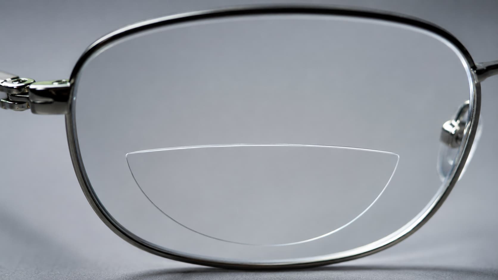 Macro close-up of a single eyeglass lens showing the curved bifocal segment line
