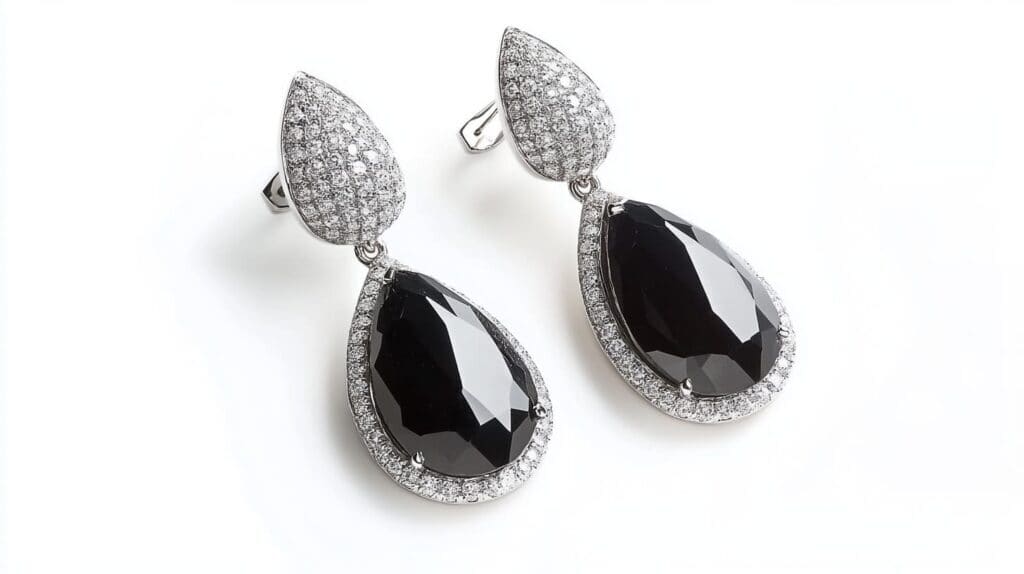 Luxurious pear-shaped black diamond drop earrings framed by a halo of white diamonds, set in silver, displayed against a white background.