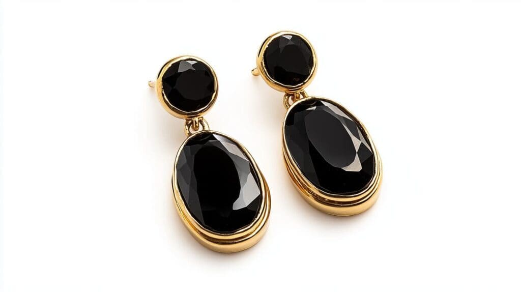 A pair of black onyx drop earrings with faceted oval gemstones set in gold, blending classic elegance with bold style.
