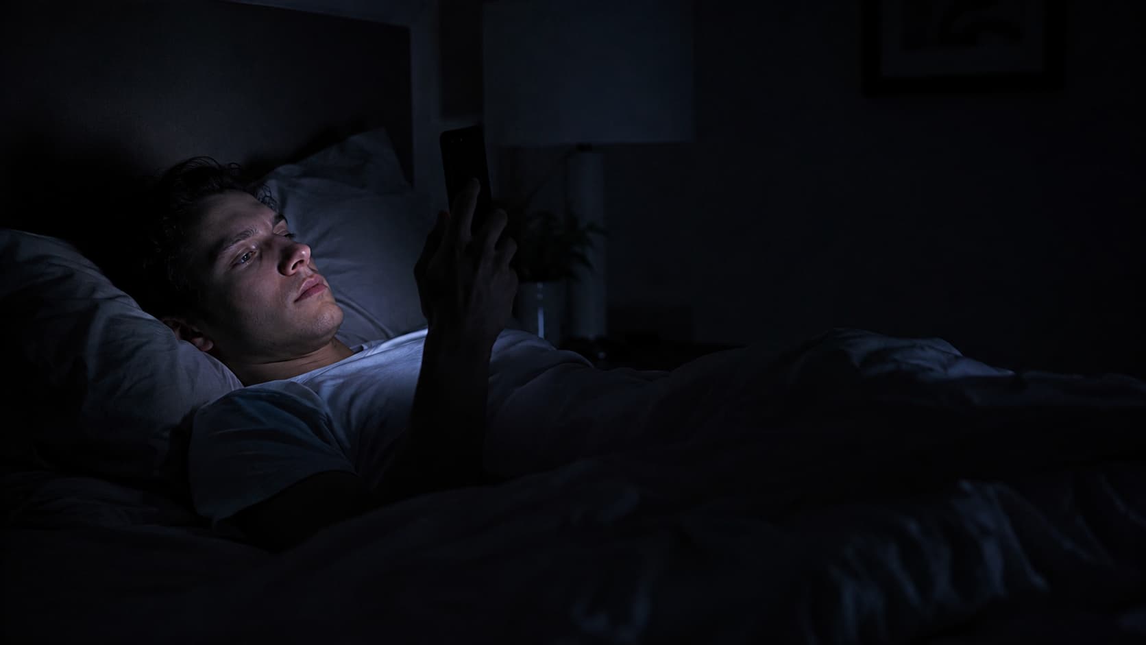 Man looking at phone in bed at night before sleep