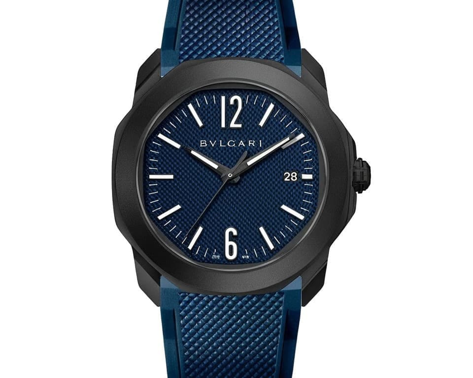 Bulgari Aluminum collection sports watch featuring blue textured dial, black carbon case, blue rubber strap, and date display representing modern luxury sportswear timepieces