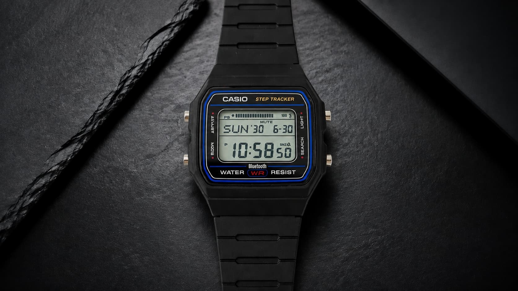 Casio Collection F-B100W-1AEF digital watch with Bluetooth step tracker on a dark background