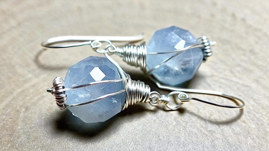 Faceted celestite gemstone earrings with silver wire wrap setting, showcasing the pale blue color and protective jewelry design