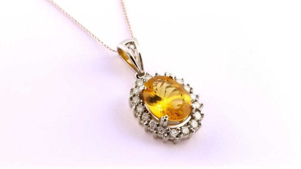 Oval citrine pendant surrounded by a halo of diamonds in a silver setting on a delicate chain