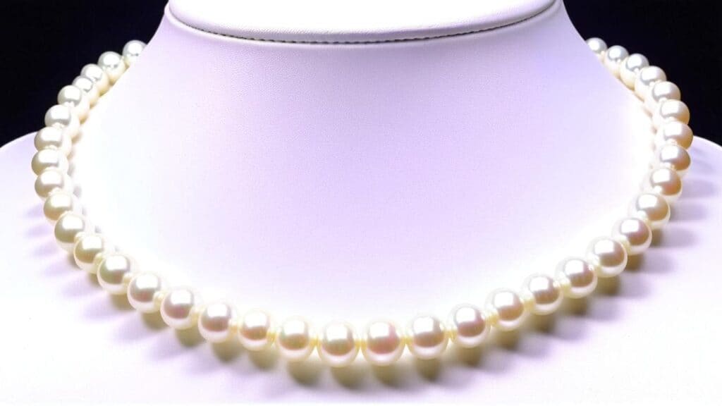 Single strand white pearl necklace displayed on a bust, representing timeless elegance and the natural luster of cultured pearls.