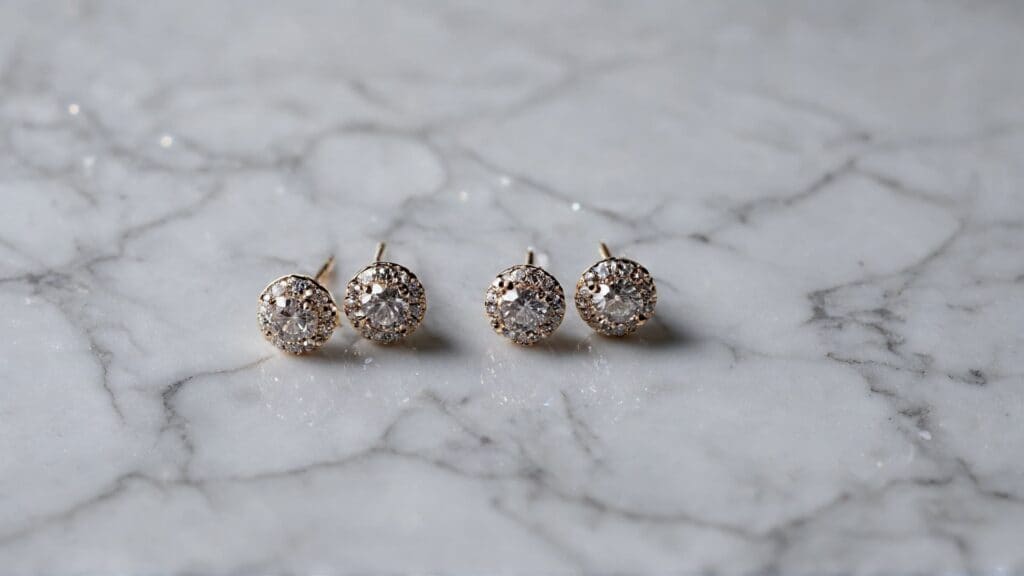 Clean gold diamond stud earrings displayed on marble surface demonstrating proper jewelry cleaning and care