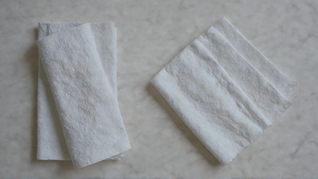 Clean white paper towels folded on white surface, essential supplies for safe piercing aftercare and cleaning