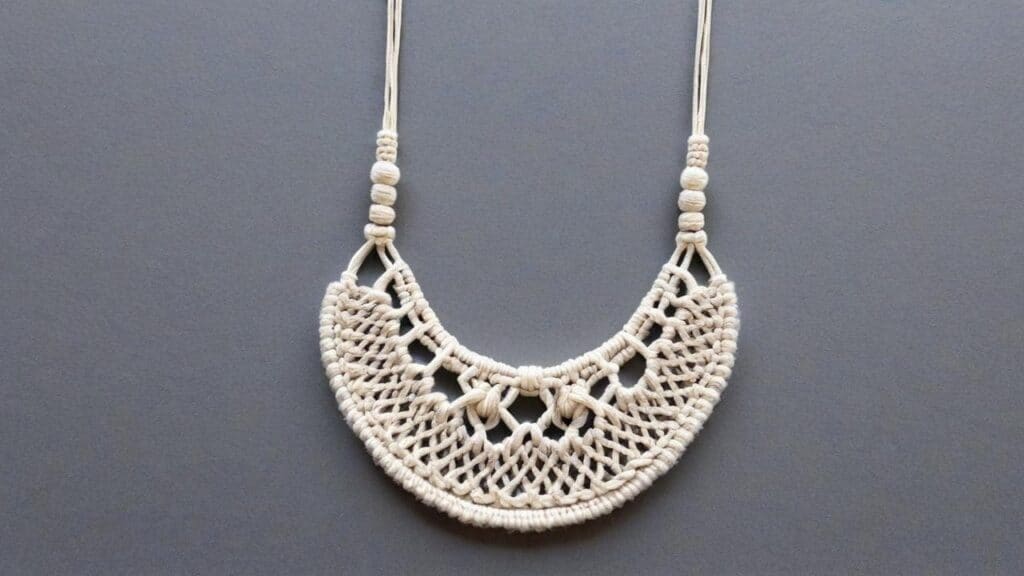 White cotton macramé statement necklace with intricate knotted pattern on grey background