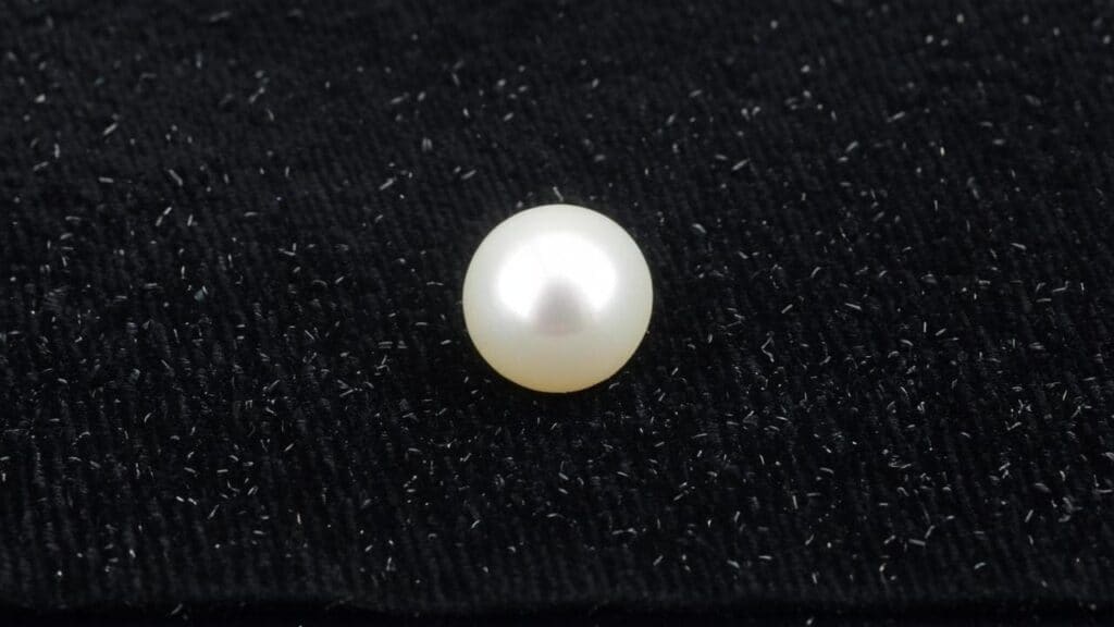 High-quality cultured pearl showcased on textured black velvet fabric for jewelry display.