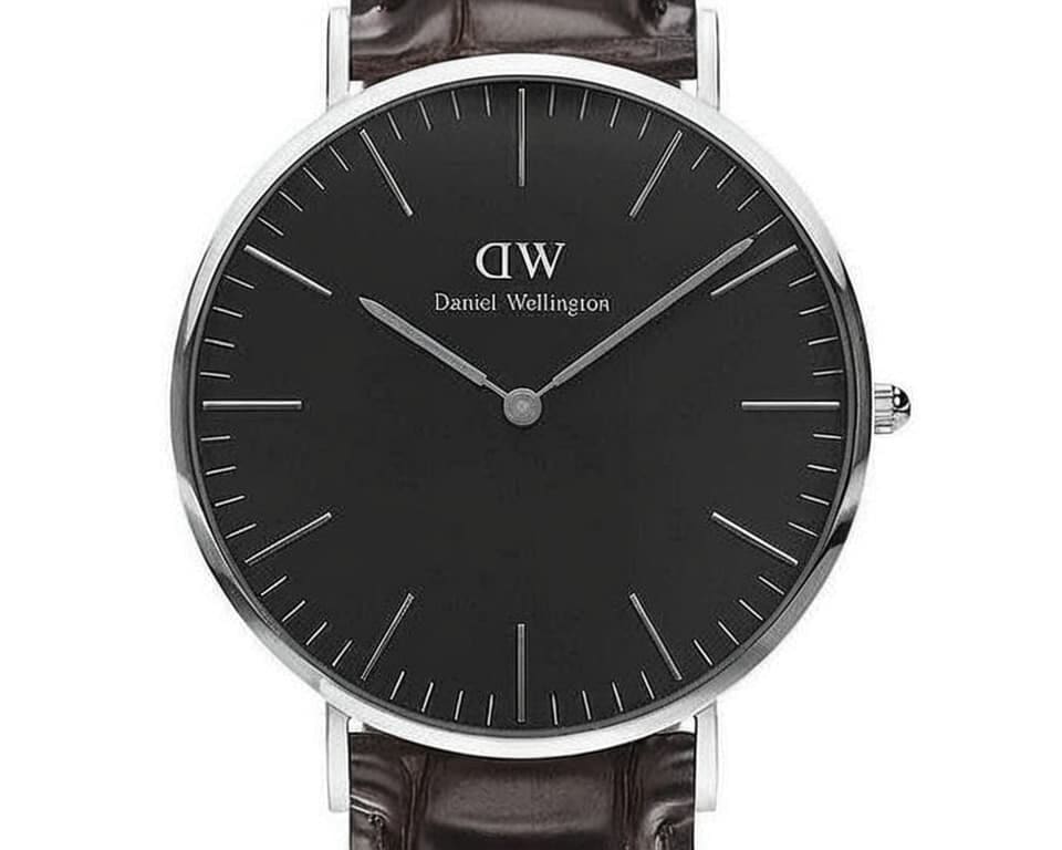 Close-up view of Daniel Wellington watch with black dial and silver case on leather strap highlighting the clean twelve index design and ultra-thin profile