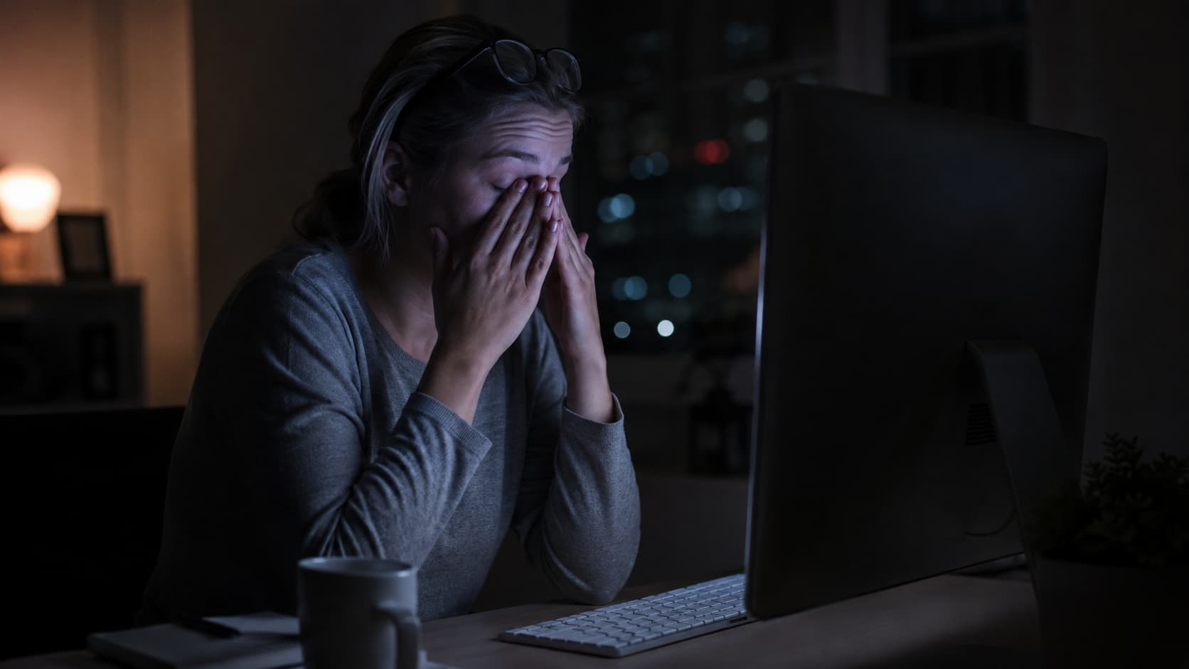 Woman rubbing tired eyes from digital eye strain at computer