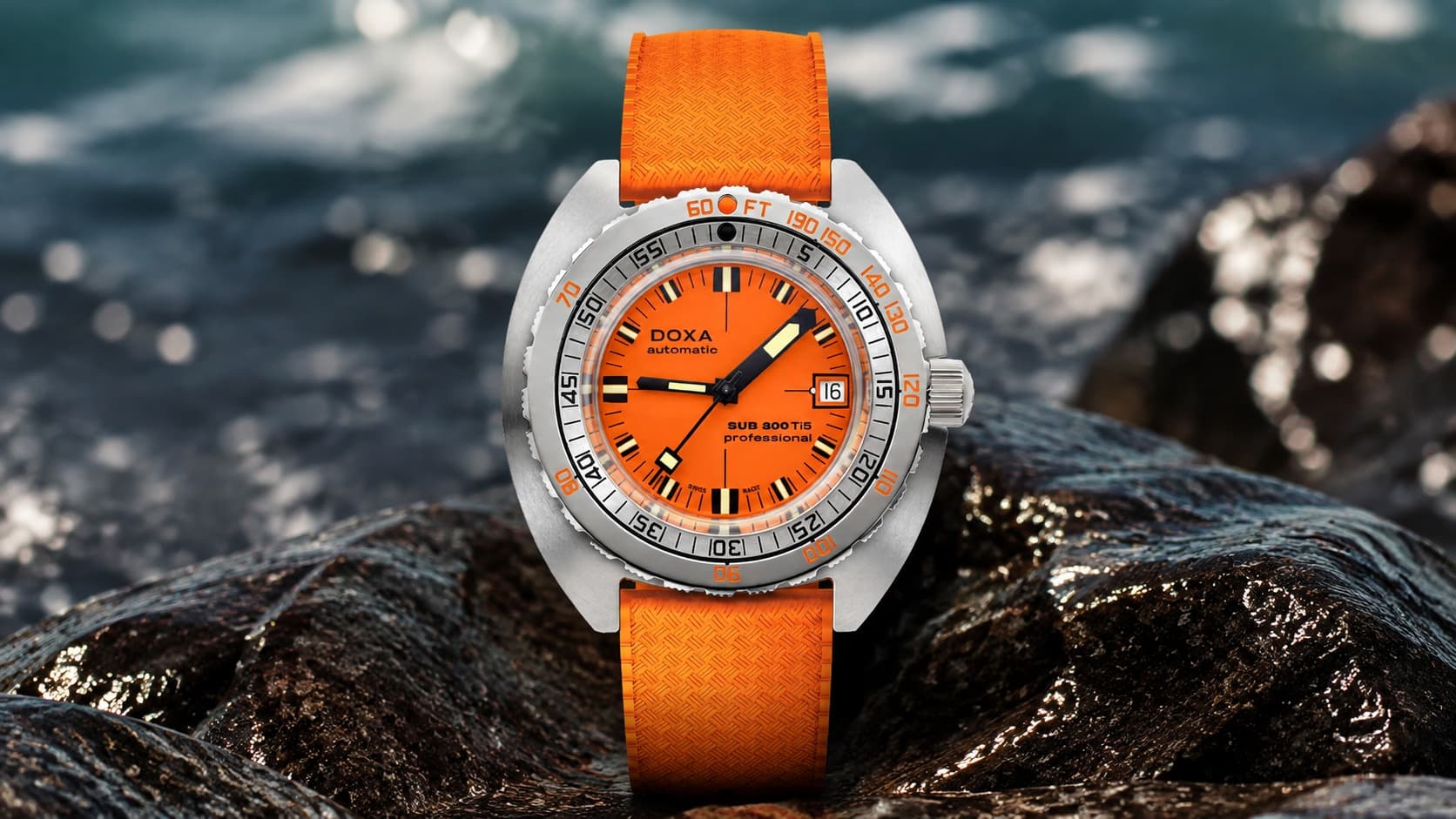 Doxa SUB 300 Ti5 Professional orange dial dive watch resting on wet rocks by the ocean