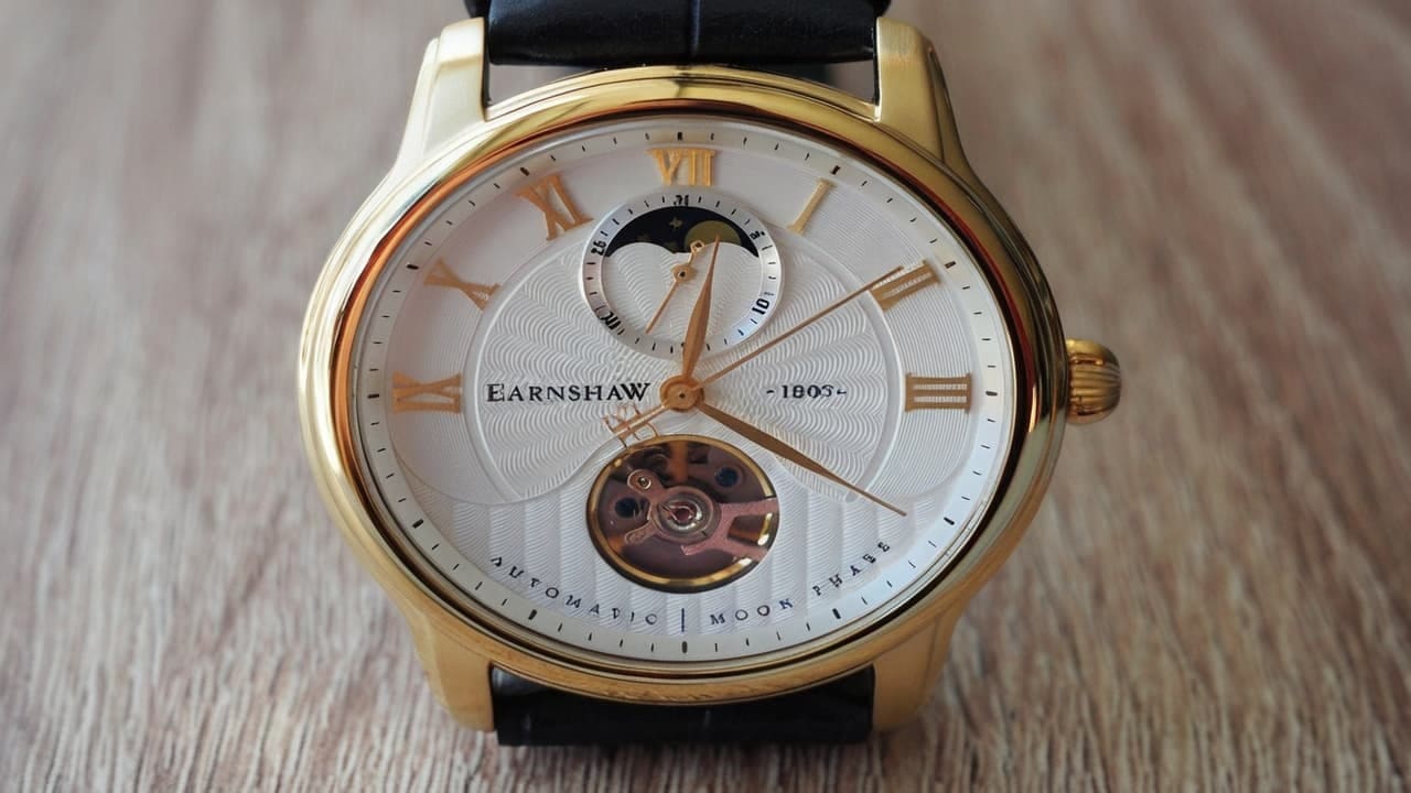 Gold Earnshaw watch with moon phase, open balance wheel and guilloche white dial