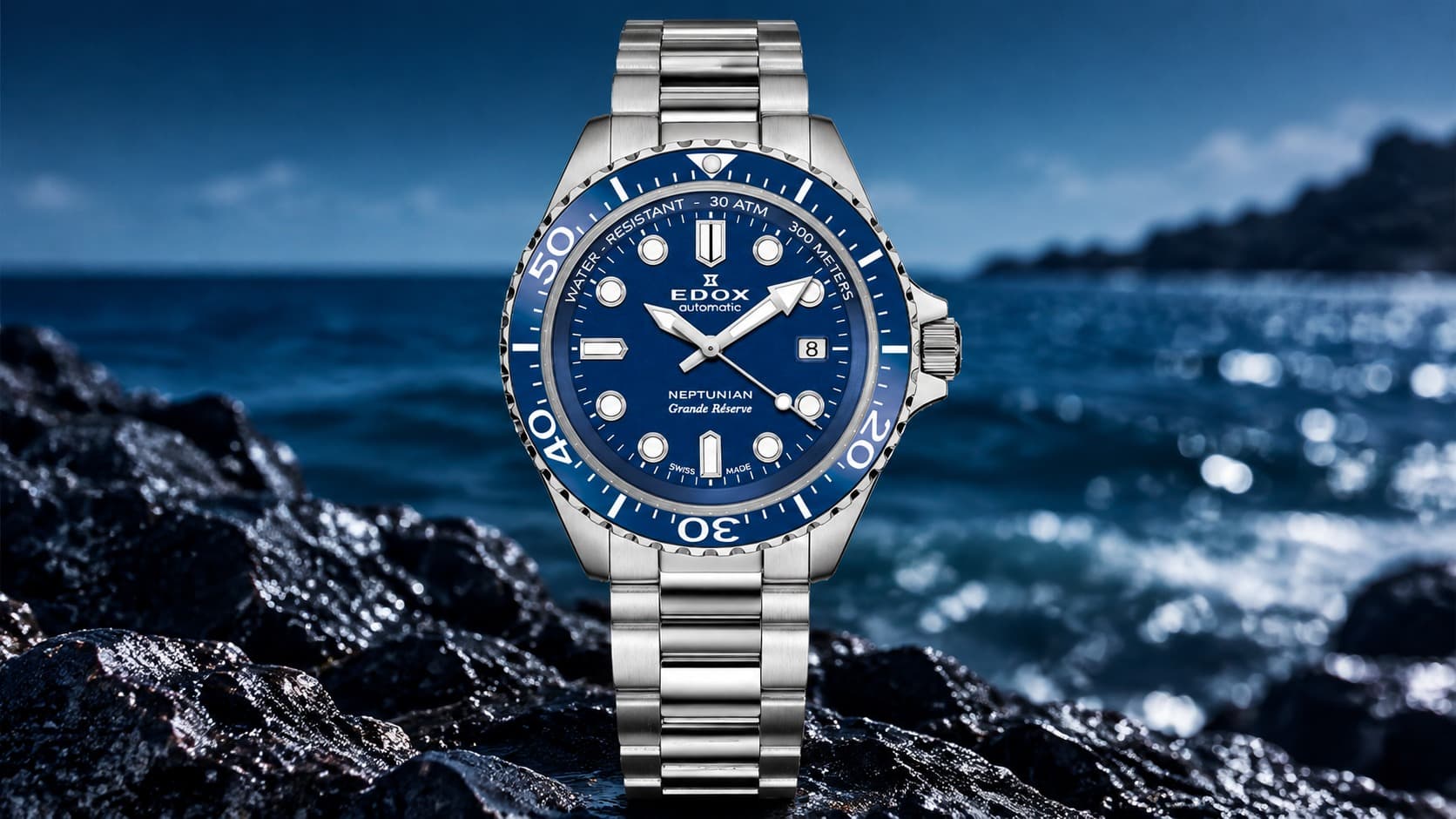 Edox Neptunian Grande Réserve Date Automatic dive watch with blue dial resting on wet rocks by the ocean