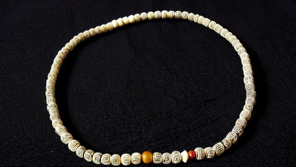 Handcrafted circular bone bead necklace featuring engraved tribal patterns on a black background