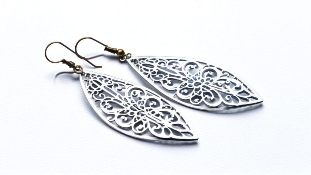 A pair of intricately designed leaf-shaped filigree iron earrings with brass hooks, displayed on a white background.