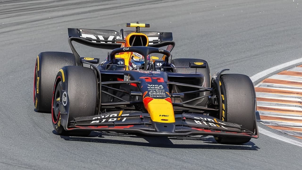 Formula 1 car in navy, red and yellow livery cornering on a racetrack