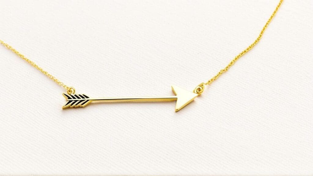 Gold arrow pendant necklace representing Sagittarius symbolism on delicate chain