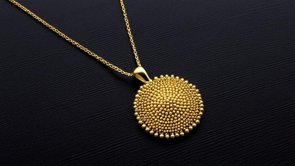 A gold pendant necklace with an elaborate granulation design, featuring hundreds of tiny gold beads forming a textured circular pattern.