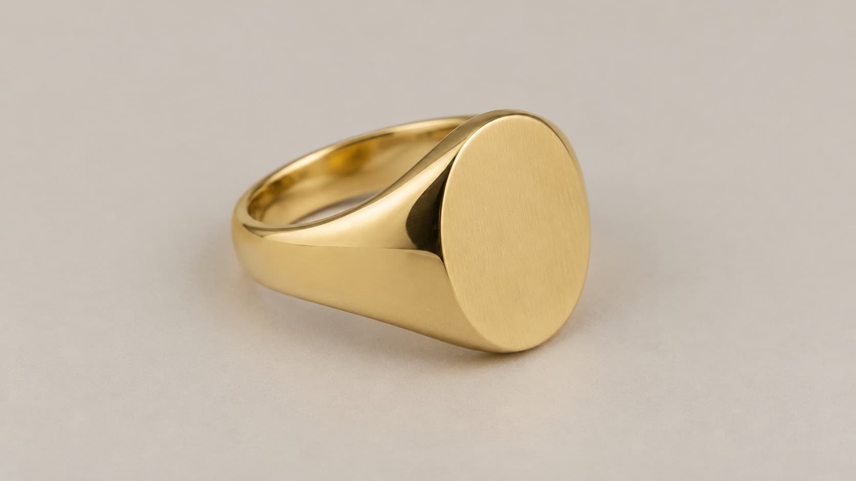 Gold signet ring with an oval engraved bezel, polished finish