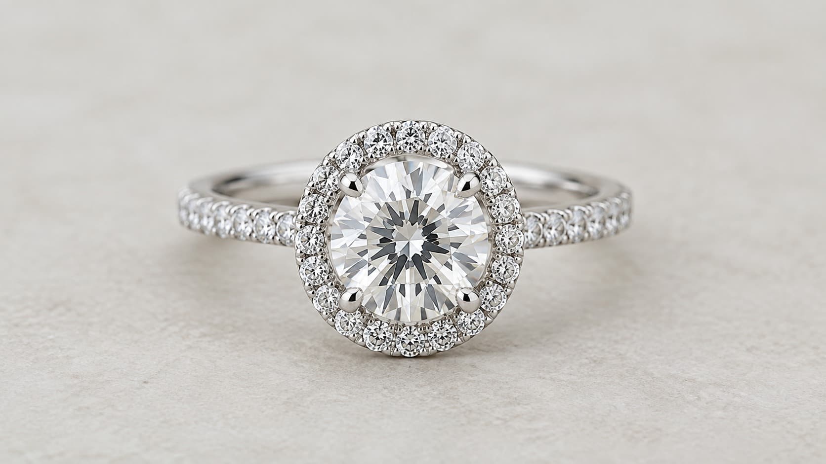 Single halo engagement ring with a round center diamond surrounded by a ring of pavé diamonds in a white gold band
