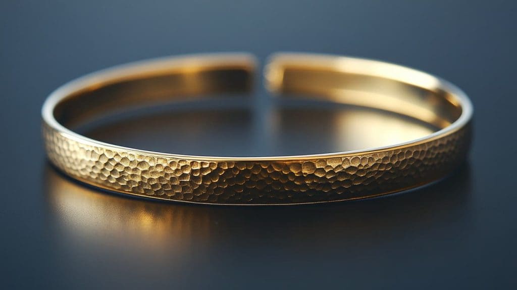 A handcrafted 16K gold bangle bracelet with a textured hammered finish, emphasizing its artisanal quality and durability.