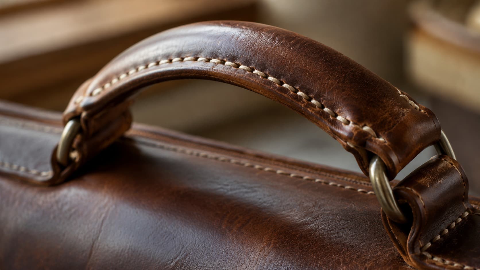 Close-up of a hand-stitched leather bag handle showing saddle stitching