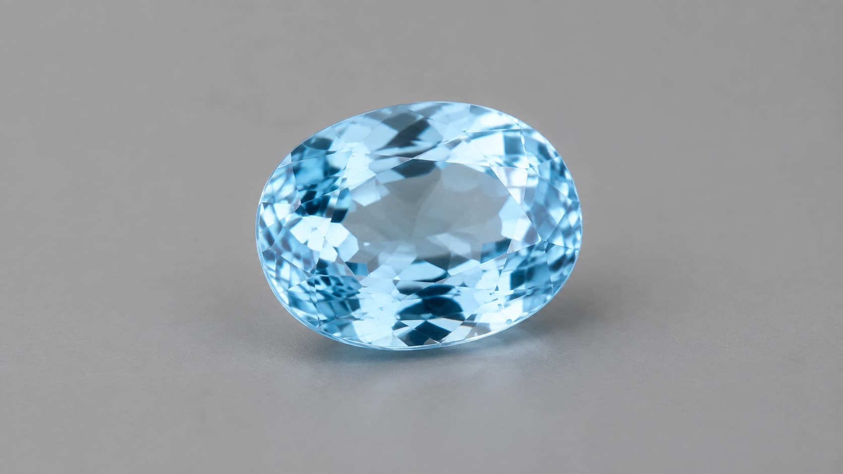 Faceted sky-blue jeremejevite gemstone on a neutral gray background