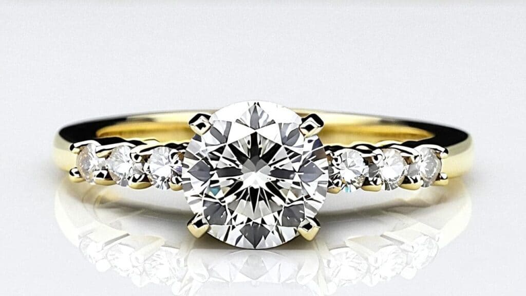 A yellow gold engagement ring with a round-cut diamond and side stones, illustrating the importance of jewelry inspections for valuation and structural integrity.