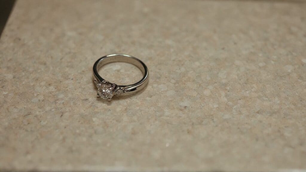 Diamond engagement ring sitting on bathroom counter near hair styling area