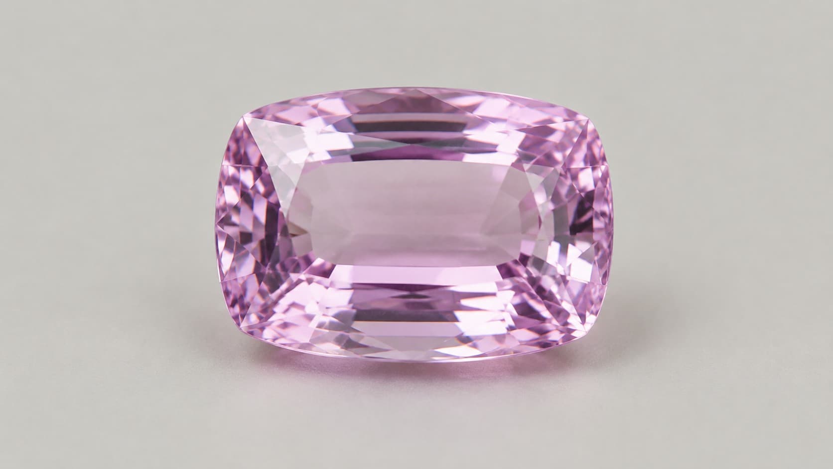 Close-up of a faceted pink-violet kunzite gemstone in a cushion cut, highlighting its clarity and faceting
