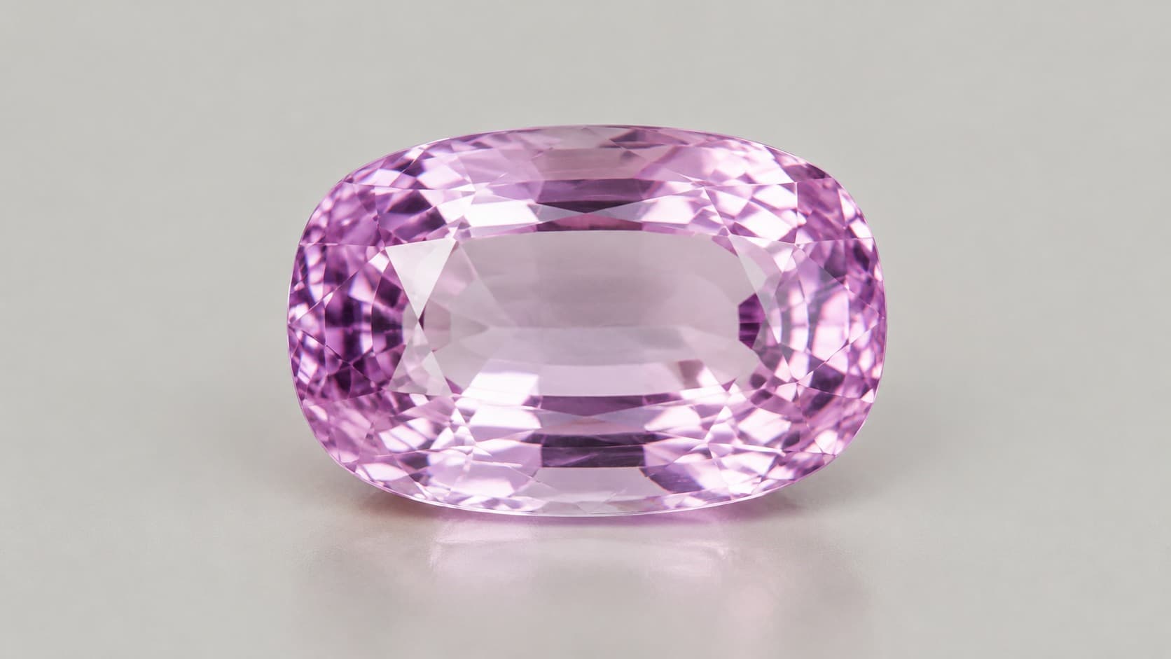 Faceted pink kunzite gemstone in an oval cut, showing its soft pink color and brilliant facets