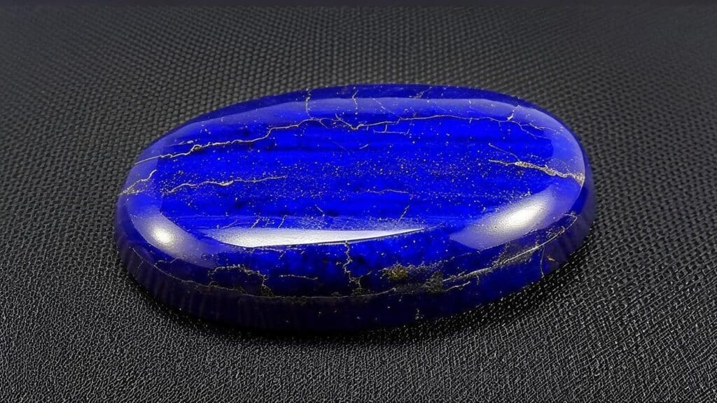 Deep blue lapis lazuli cabochon with golden pyrite inclusions and smooth polish