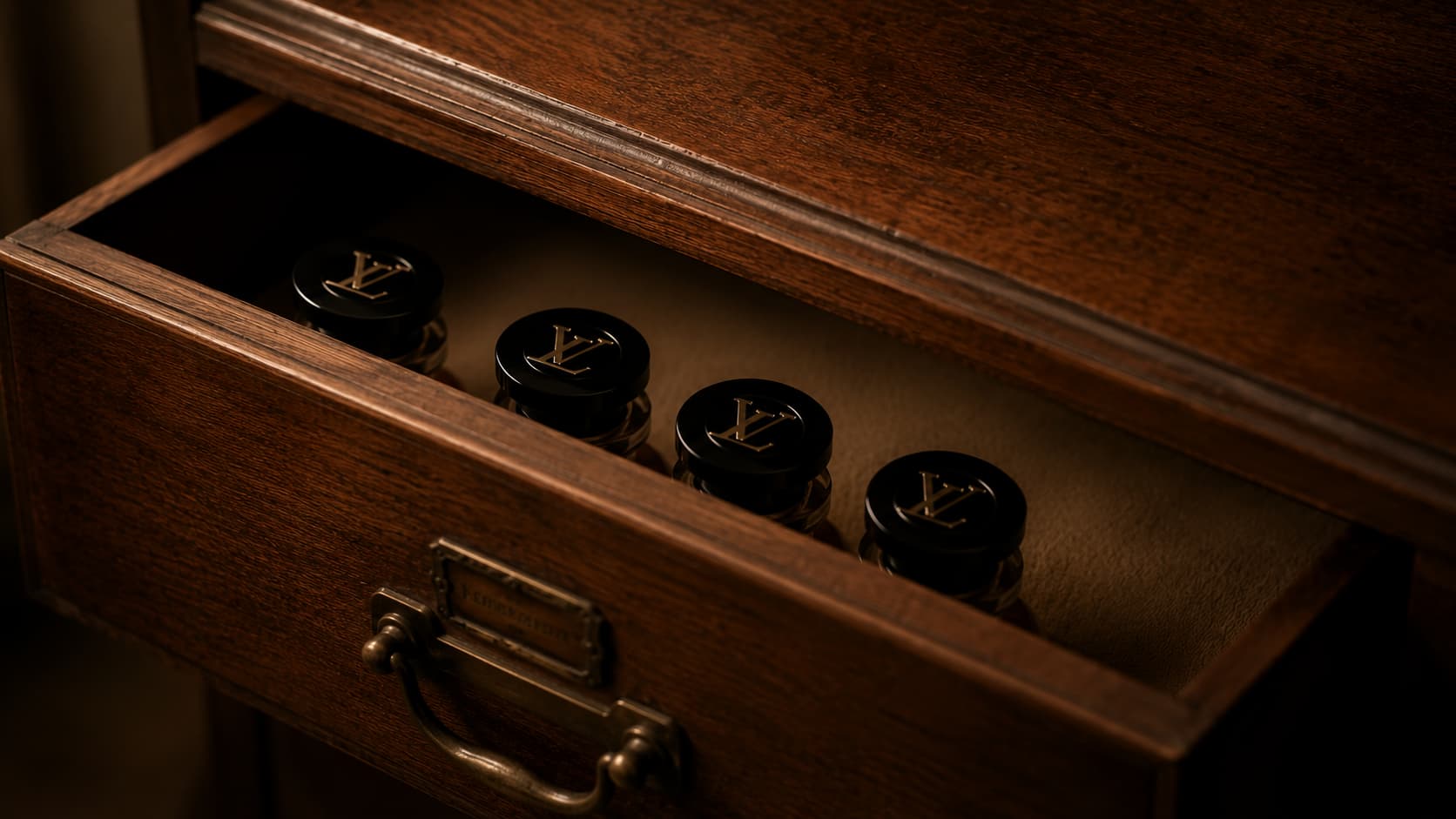 Four Louis Vuitton perfume bottles stored inside a dark wooden drawer