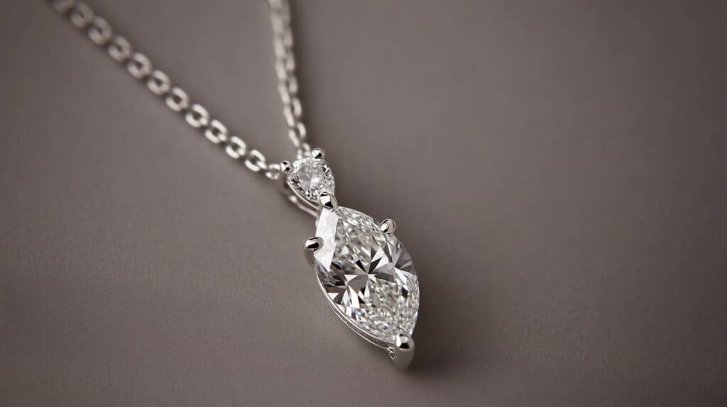 A delicate marquise cut diamond pendant necklace set in white gold, featuring an additional round diamond accent for extra sparkle.