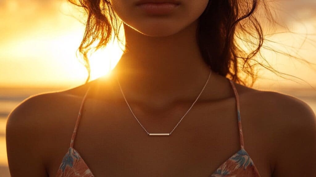 Minimalist gold bar necklace worn at sunset on the beach, complementing a casual summer outfit.