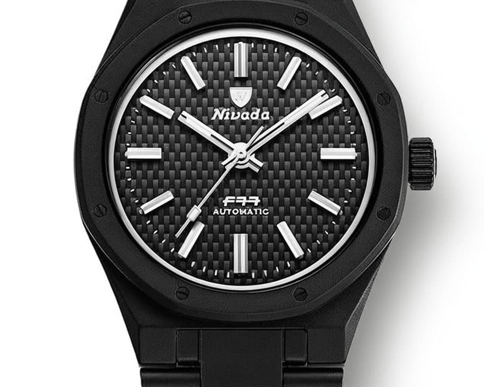 Nivada Grenchen automatic watch with black carbon fiber textured dial, octagonal black case, and integrated black bracelet on white background