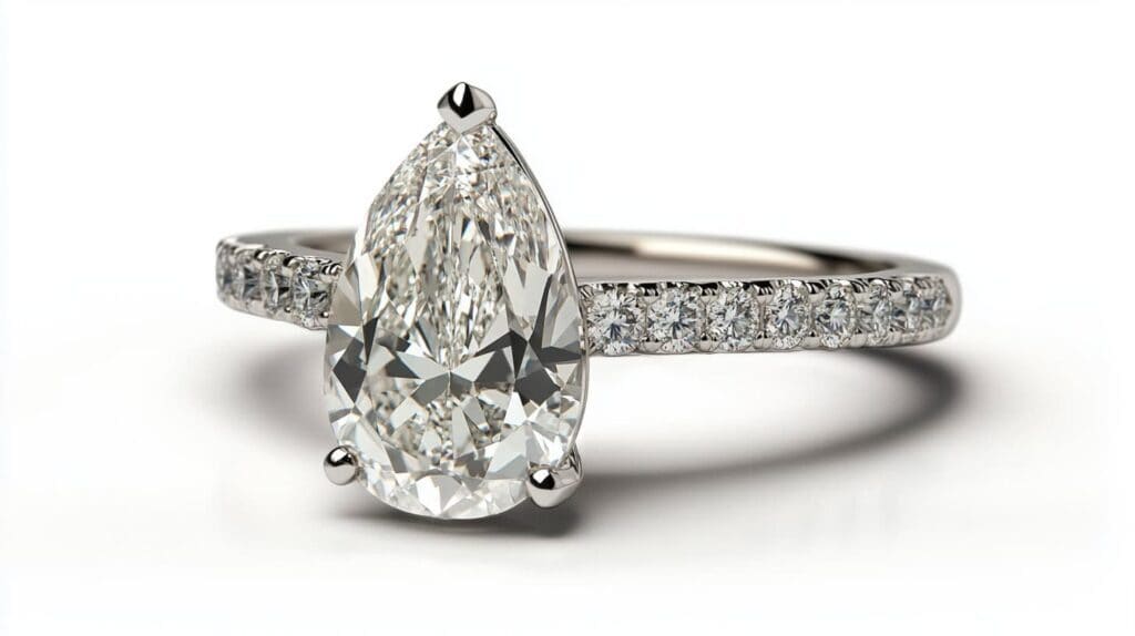 A pear-shaped diamond engagement ring set in white gold with a pave band, featuring a classic and elegant design.