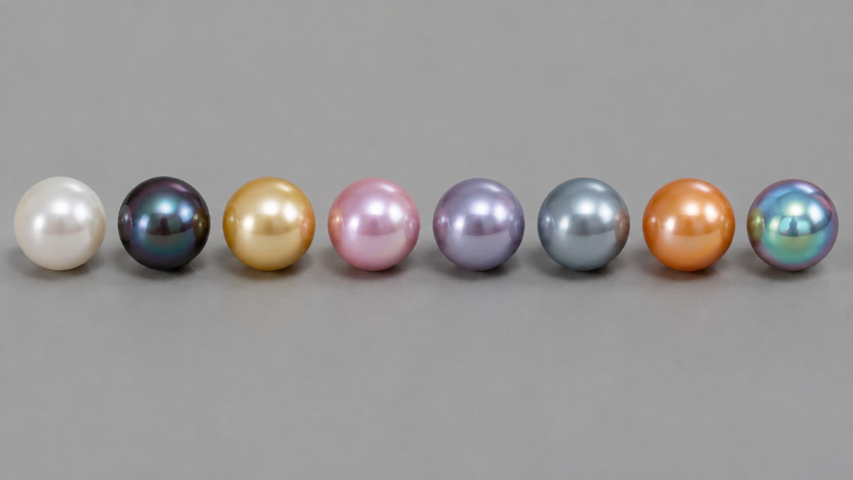 Row of natural pearls in every color: white, black, gold, pink, lavender, blue, orange, and iridescent green