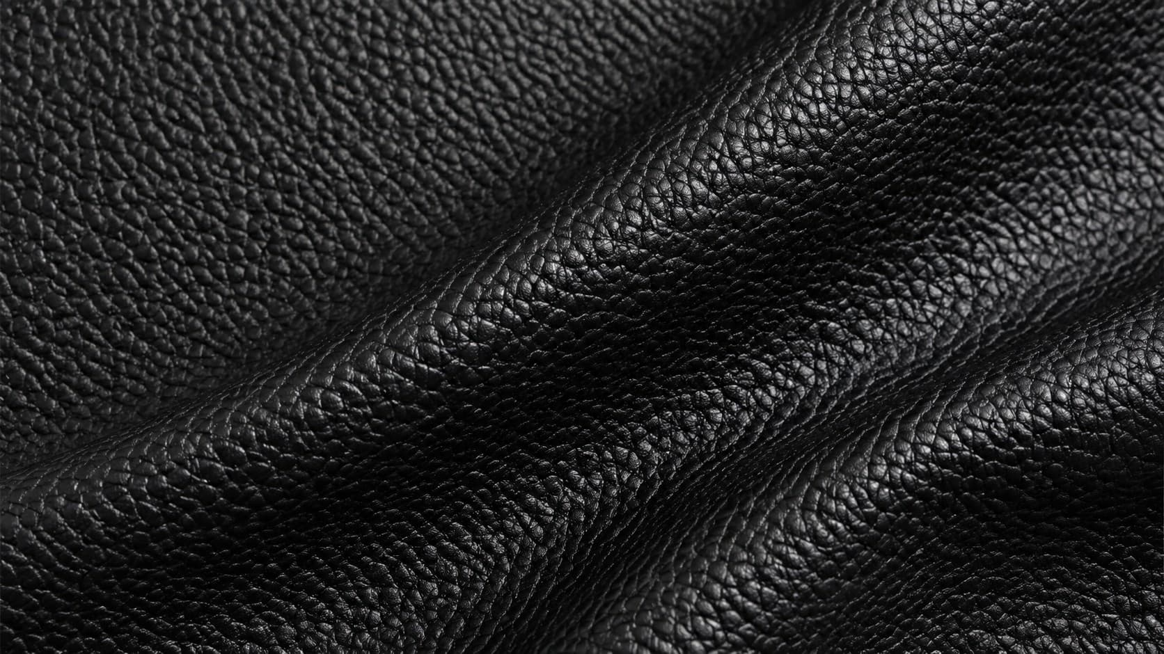 Close-up of black pebbled leather with deep folds showing the bumpy grain texture
