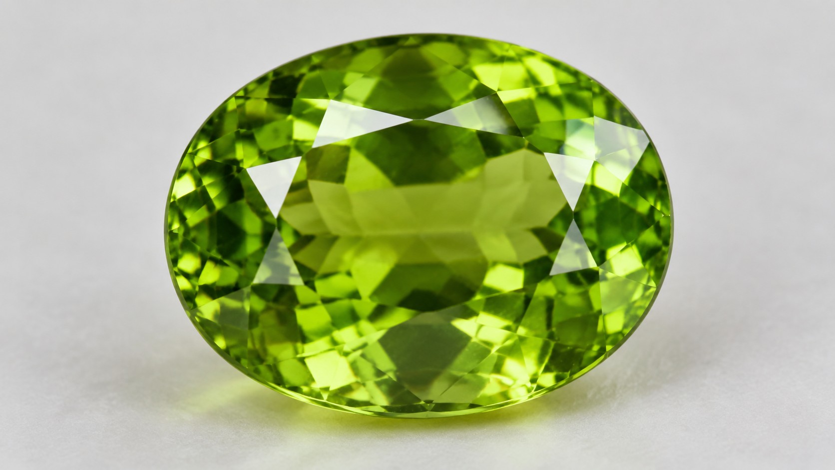 Faceted bright green peridot gemstone on a neutral background
